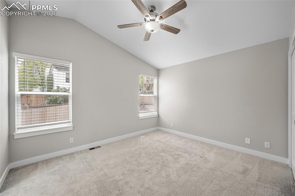 Image 24 of 36: Vaulted ceiling bedroom featuring light gray walls, carpet flooring, a ceil