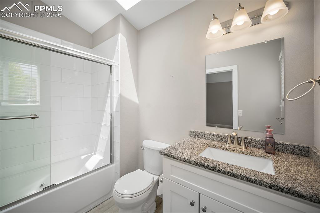 Image 26 of 36: Bathroom featuring a vanity with a granite-style countertop, an undermount 