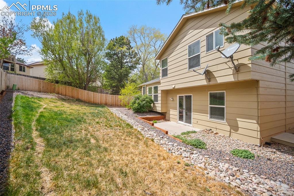 Image 28 of 36: Expansive backyard featuring a privacy fence, mature trees, and a concrete 