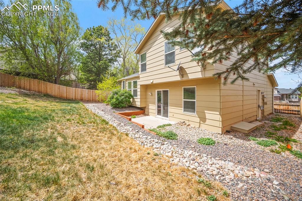 Image 29 of 36: Two-story exterior with light beige siding, featuring a ground-level patio