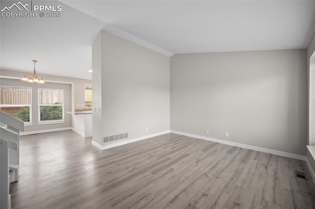 Image 4 of 36: Spacious room featuring light wood-finish flooring, white baseboards, and n