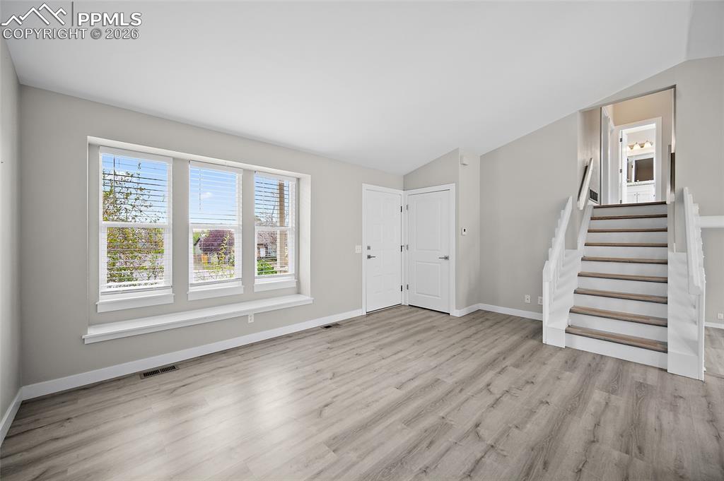 Image 5 of 36: Open-concept living space featuring wood-finish flooring, a three-panel win