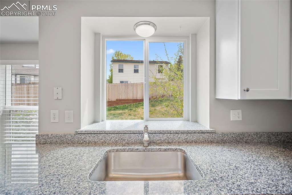 Image 8 of 36: Kitchen featuring a double basin stainless steel sink, speckled granite cou