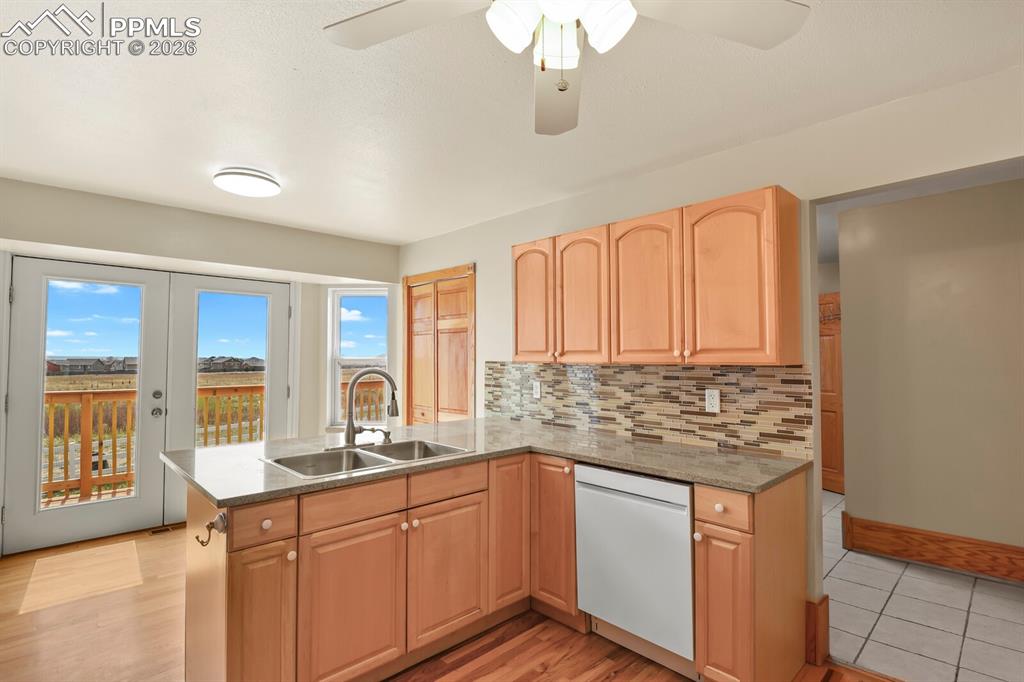 Image 11 of 37: Kitchen with a peninsula, light wood finish cabinetry, dishwasher, ceiling 