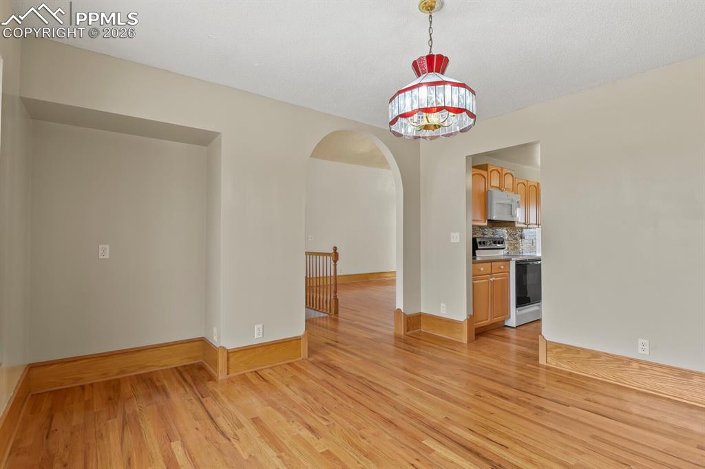 Image 14 of 37: Dining room with arched walkways and wood finished floors