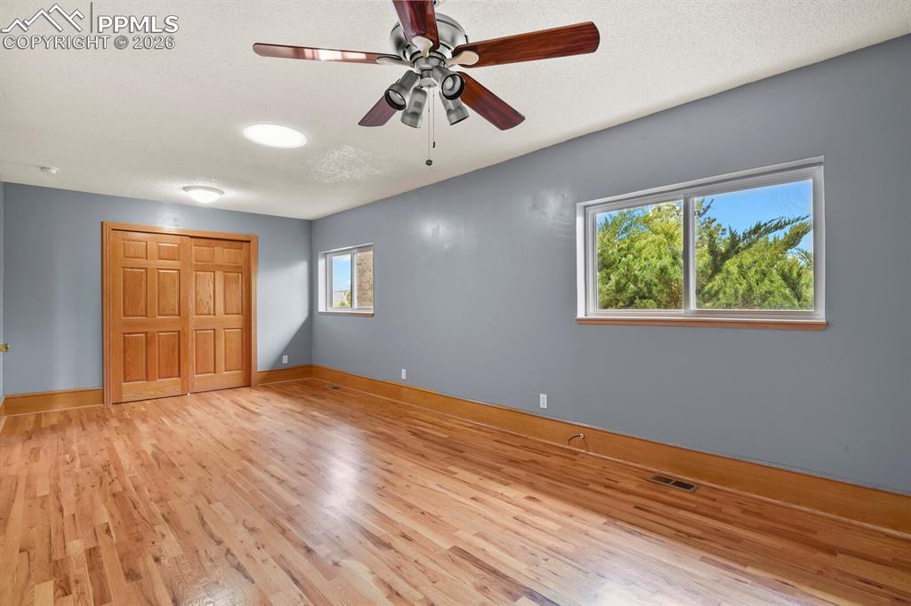 Image 15 of 37: Main Level Bedroom with ceiling fan, light wood-type flooring, and a closet