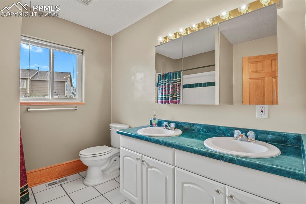 Image 17 of 37: Main Level Full bath with double vanity, a shower, and tilefloors