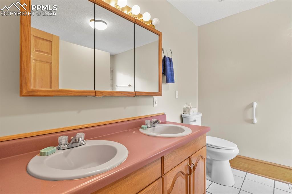 Image 19 of 37: Master bath with double vanity and tile floors