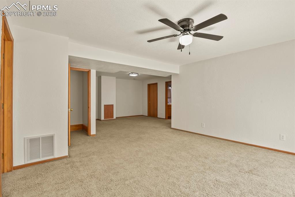 Image 24 of 37: Family room with ceiling fan and light colored carpet