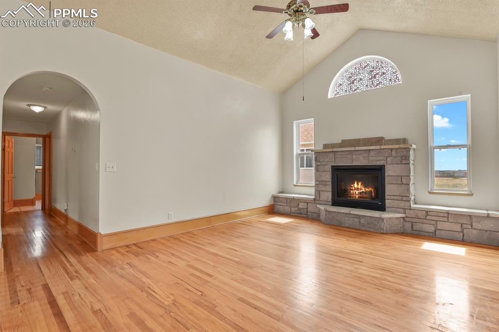Image 3 of 37: Living room with arched walkways, a high textured ceiling, light wood-type 