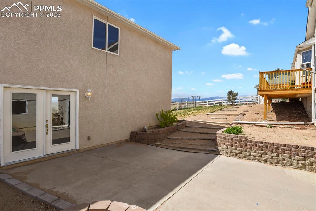Image 32 of 37: Patio Leading to Rear Stucco Building with french doors