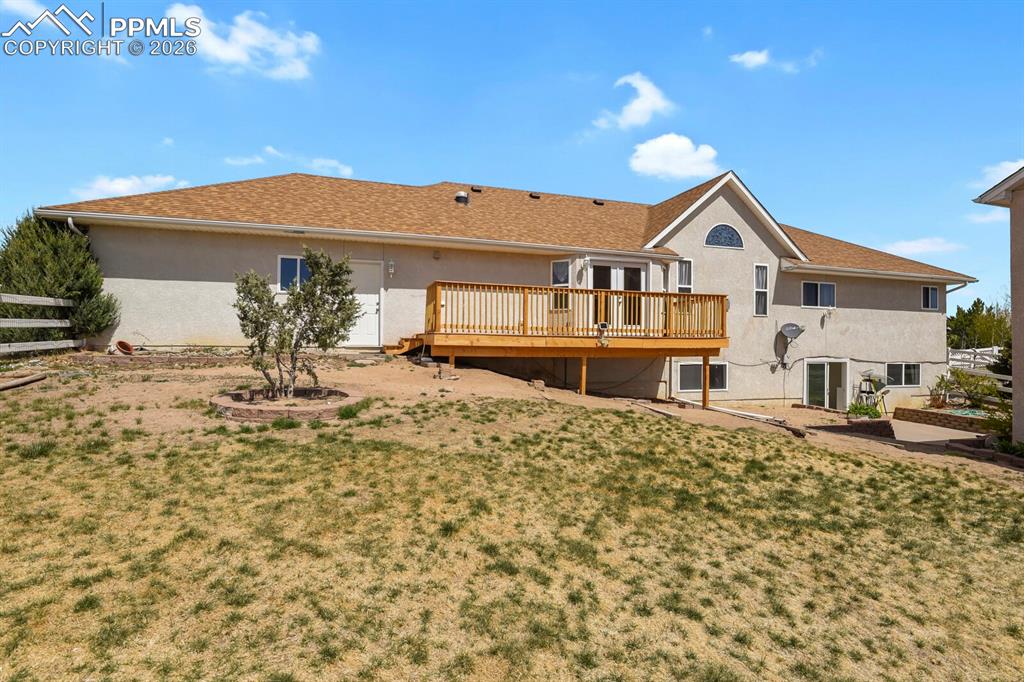 Image 35 of 37: Rear view of house featuring a wooden deck and stucco siding