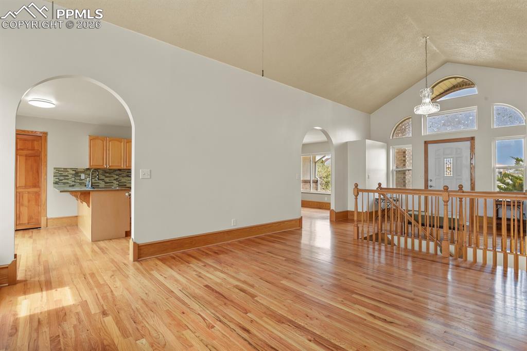 Image 5 of 37: Living room Looking Into Kithen with arched walkways, and a high ceiling