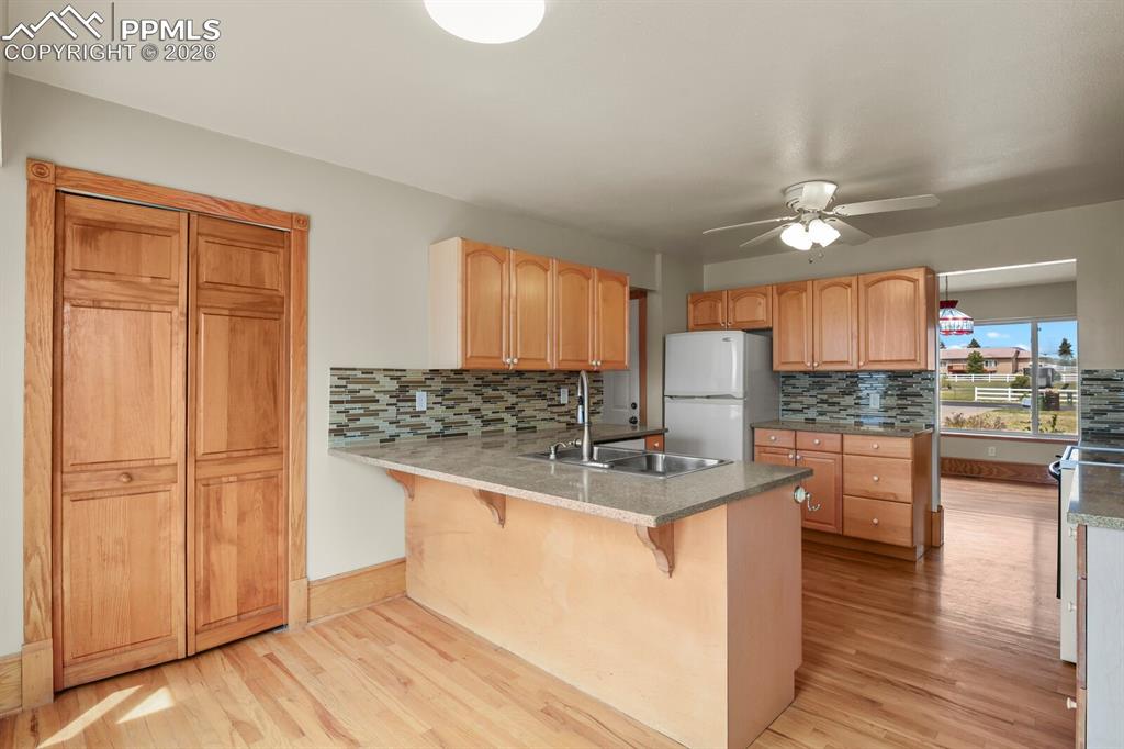 Image 8 of 37: Kitchen with a kitchen breakfast bar, a peninsula, freestanding refrigerato