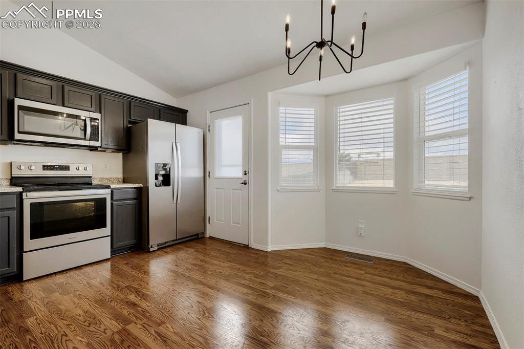 Image 12 of 32: Open-concept kitchen and dining area featuring rich wood-finish flooring, d