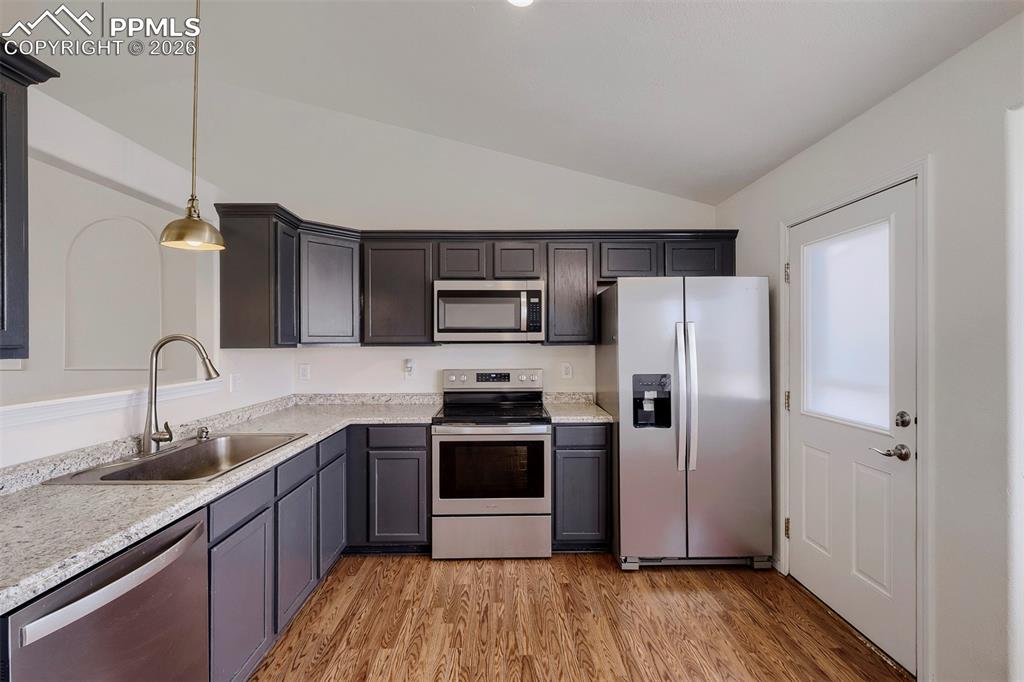Image 14 of 32: Modern kitchen featuring dark cabinetry, speckled countertops, stainless st