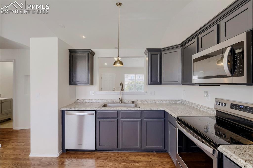 Image 16 of 32: Kitchen featuring dark cabinetry, light-toned countertops, a stainless stee