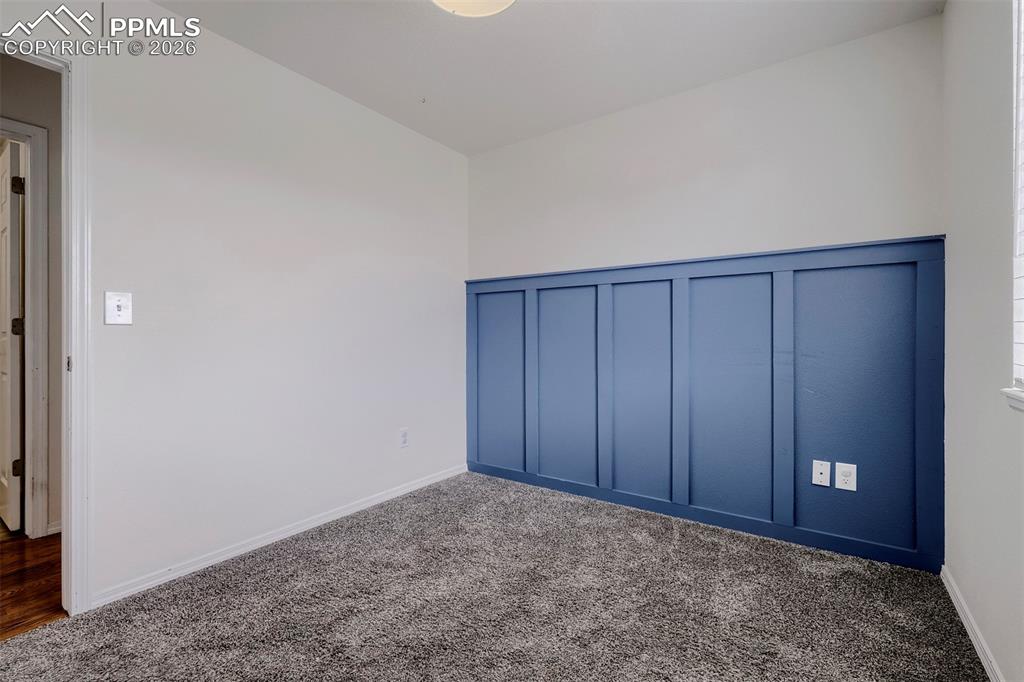 Image 24 of 32: Room featuring a blue board and batten accent wall, light gray textured car