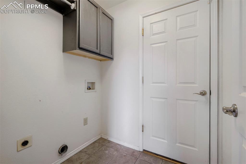 Image 27 of 32: Dedicated utility space featuring wall-mounted cabinetry, essential plumbin