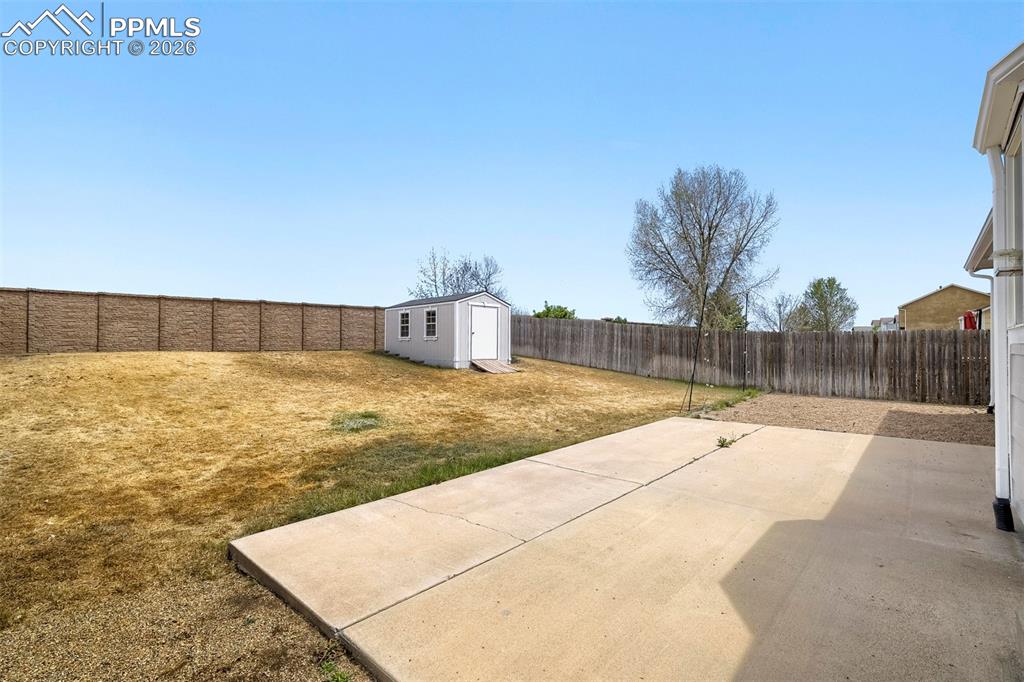 Image 28 of 32: Expansive backyard with a large concrete patio, a storage shed, and a priva