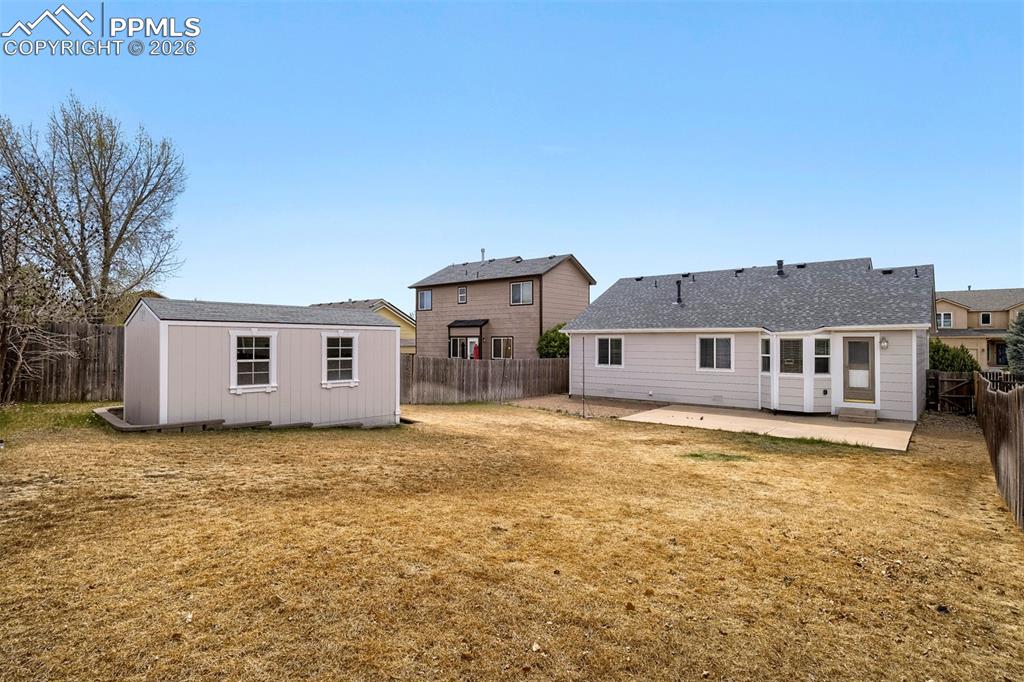 Image 31 of 32: Expansive yard featuring a detached storage shed with dual windows and a re