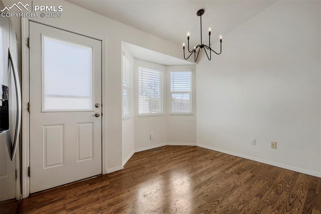 Image 4 of 32: Dining area featuring wood-finish flooring, a contemporary black chandelier