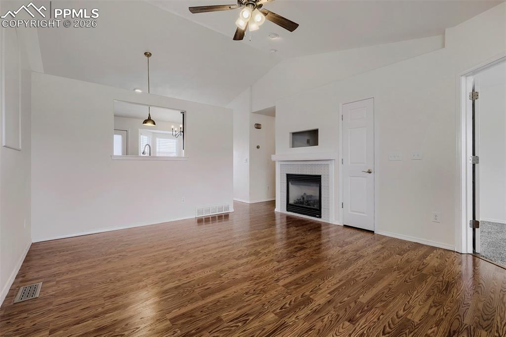 Image 9 of 32: Spacious living area featuring vaulted ceilings, wood-finish flooring, a mo