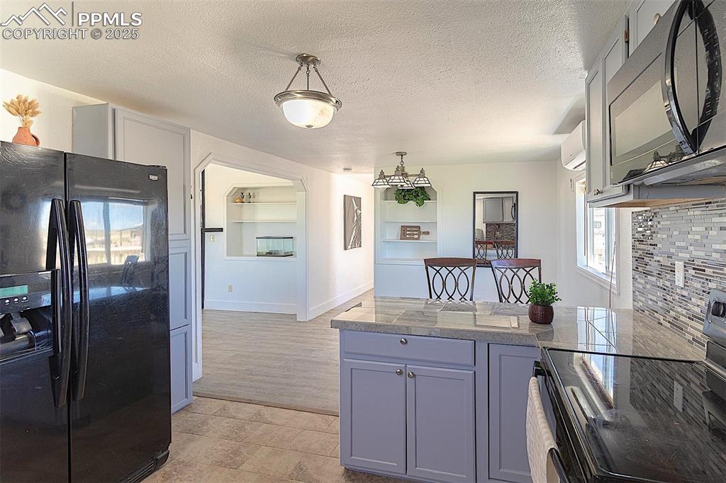 Image 10 of 38: Kitchen featuring black appliances, tile counters, a peninsula, built in fe