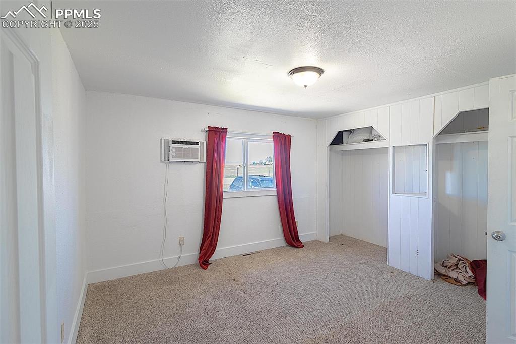 Image 11 of 38: Unfurnished bedroom featuring a wall mounted AC, light colored carpet, a te