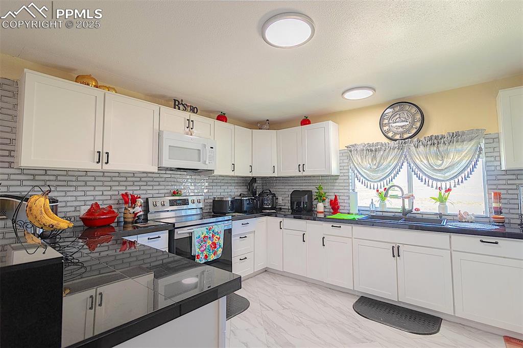 Image 19 of 38: Kitchen featuring white microwave, stainless steel electric range, a sink,