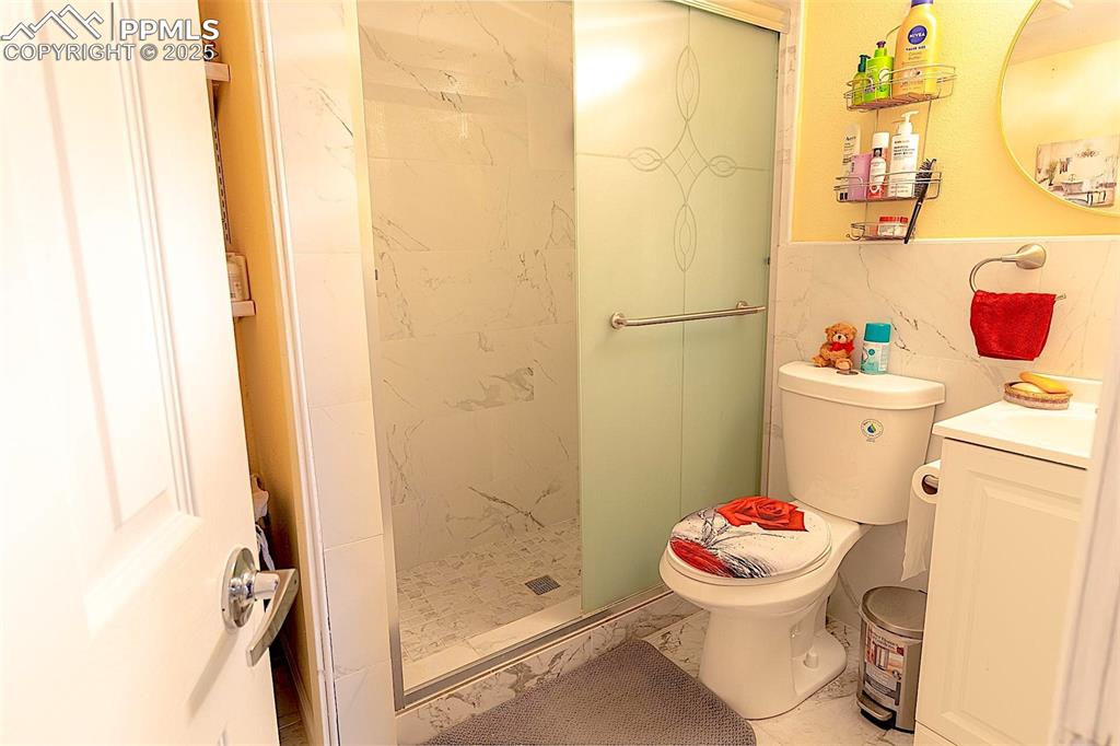 Image 24 of 38: Full bathroom featuring marble finish floors, vanity, toilet, and a shower