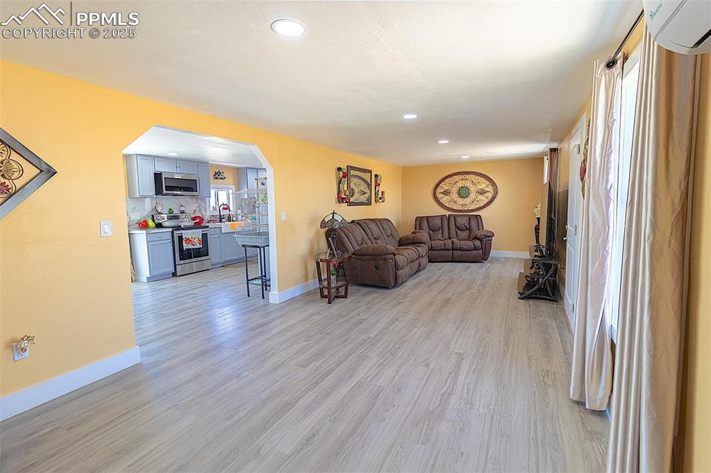 Image 31 of 38: Living area with light wood-style flooring, arched walkways, baseboards, a