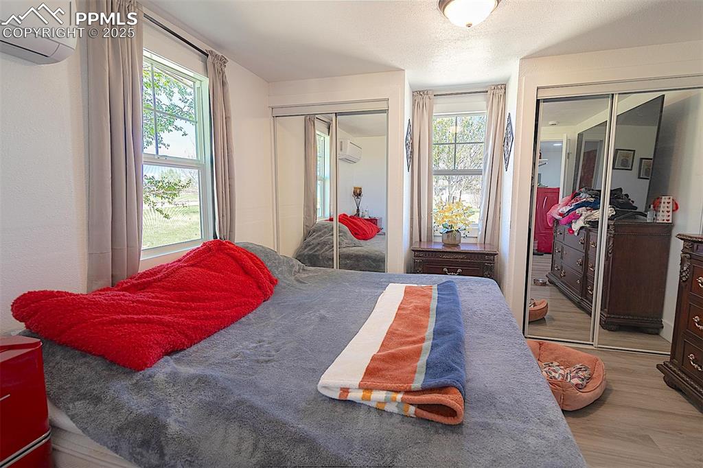 Image 35 of 38: Bedroom with an AC wall unit, two closets, and wood finished floors