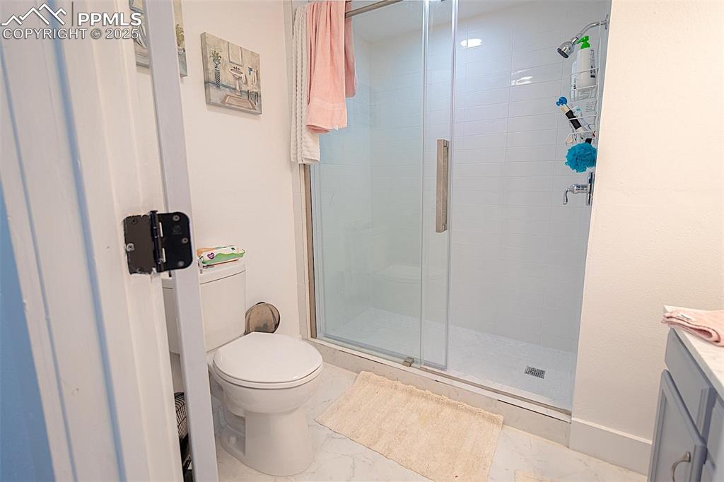 Image 36 of 38: Full bathroom with toilet, marble finish floors, vanity, a shower stall, an