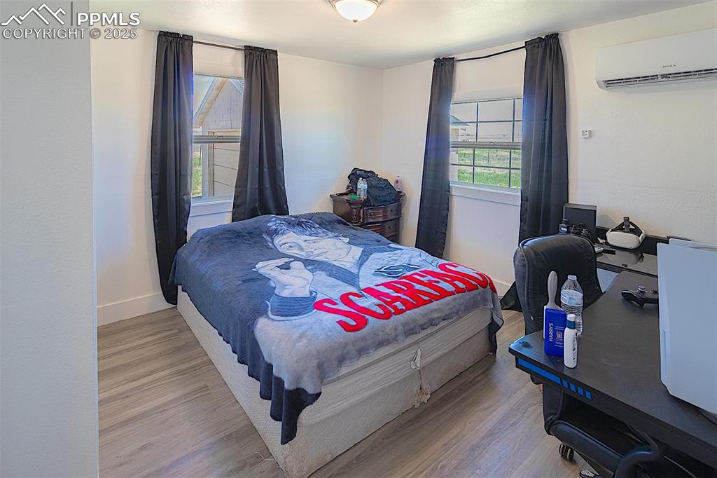 Image 37 of 38: Bedroom featuring a wall mounted air conditioner, wood finished floors, and
