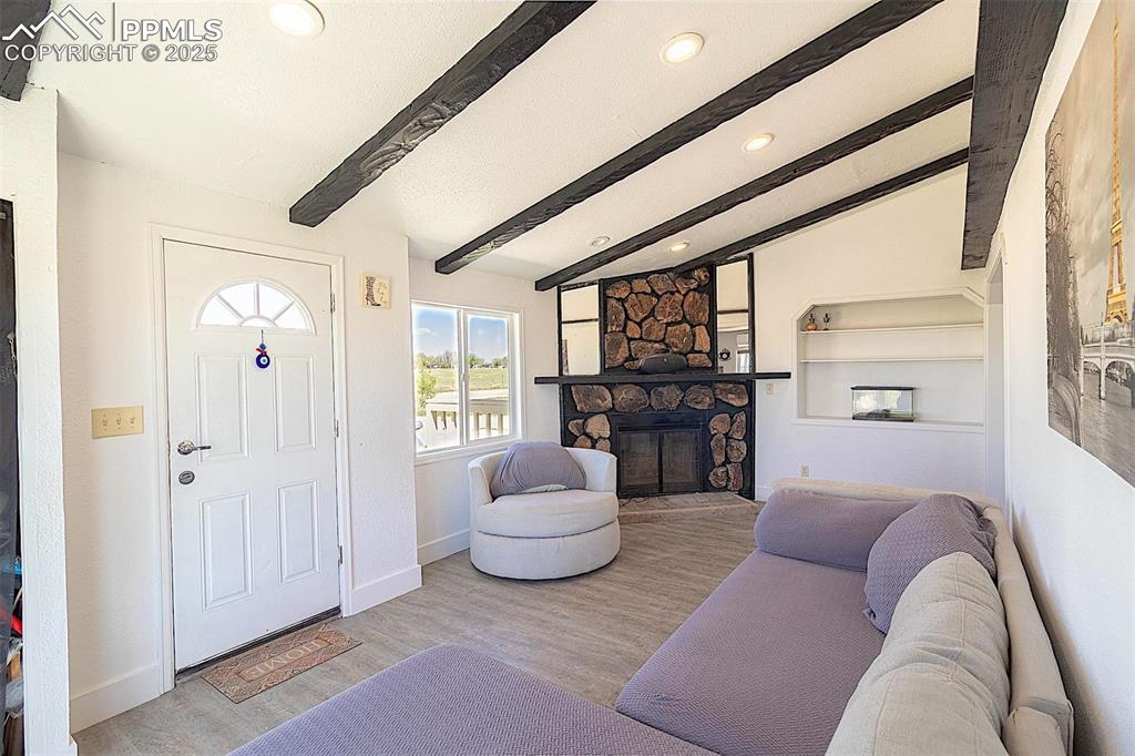 Image 8 of 38: Living area with recessed lighting, a stone fireplace, wood finished floors