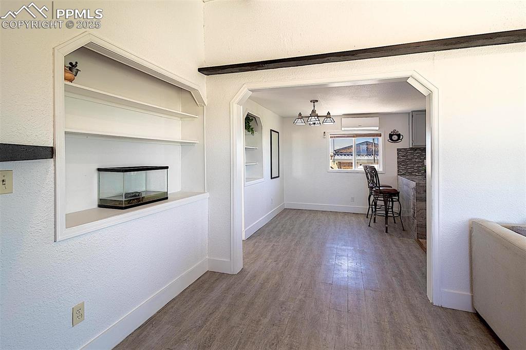 Image 9 of 38: Dining area with baseboards, wood finished floors, a wall mounted AC, a cha