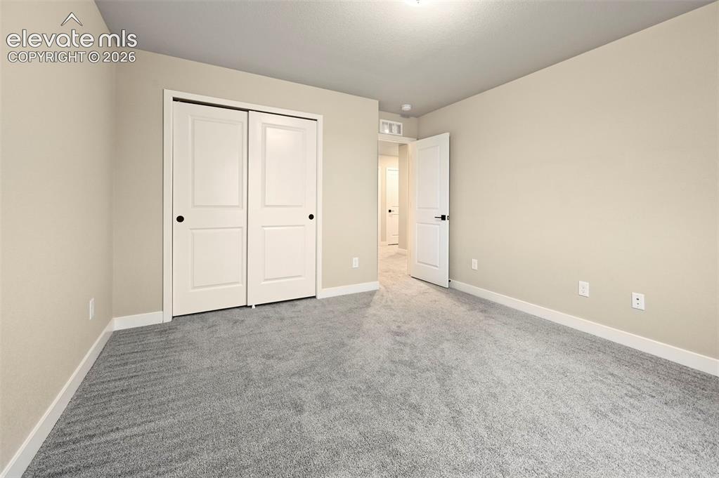 Image 12 of 28: Neutral-toned room featuring a soft gray carpet, white baseboards, and a wh