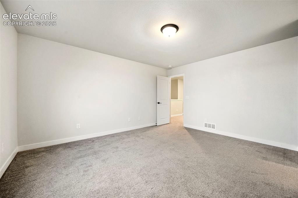 Image 13 of 28: Spacious room featuring neutral carpeting, light-colored walls, and a ceili