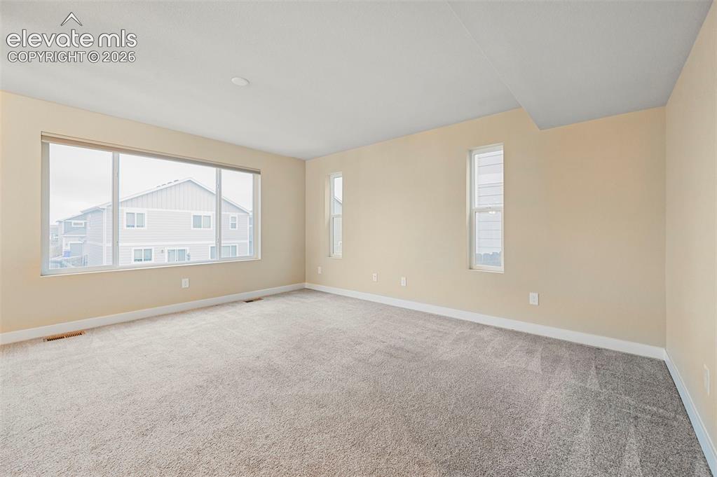 Image 16 of 28: Spacious room featuring neutral carpeting and light-toned walls