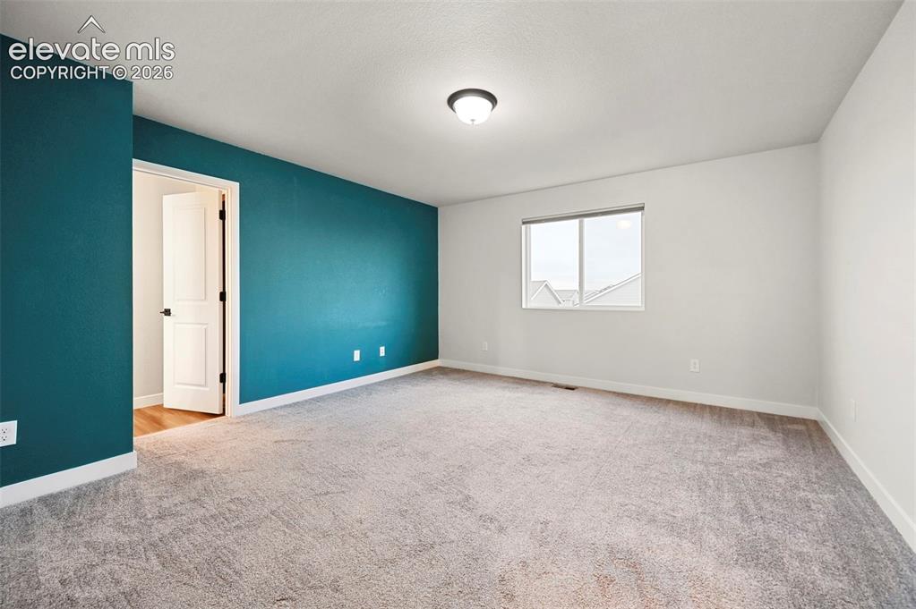 Image 18 of 28: Spacious room featuring neutral carpeting, a prominent window, a ceiling-mo