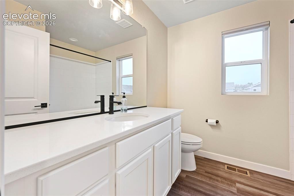Image 19 of 28: Bathroom featuring a white vanity with slab countertop, undermount sink, an