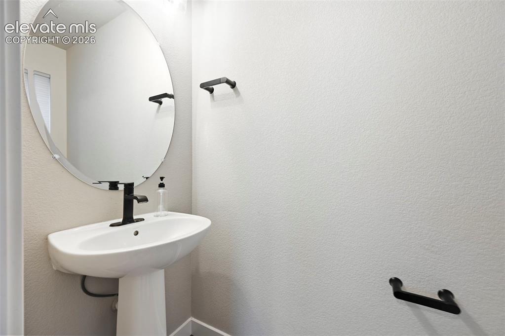 Image 21 of 28: Pedestal sink featuring a matte black single-handle faucet, oval mirror, an