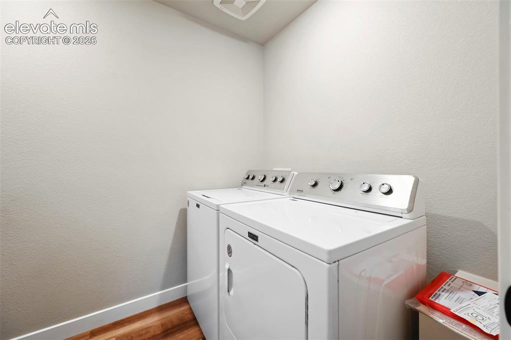 Image 22 of 28: Dedicated laundry area featuring a white washer and dryer set, wood-finish