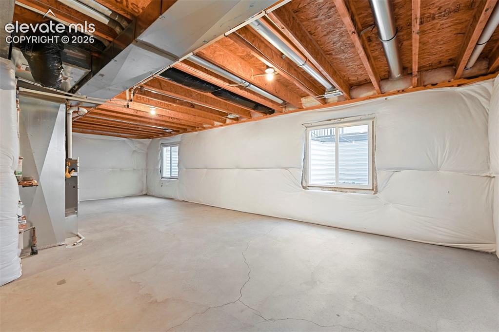 Image 23 of 28: Unfinished basement space featuring exposed wood joists and concrete floori