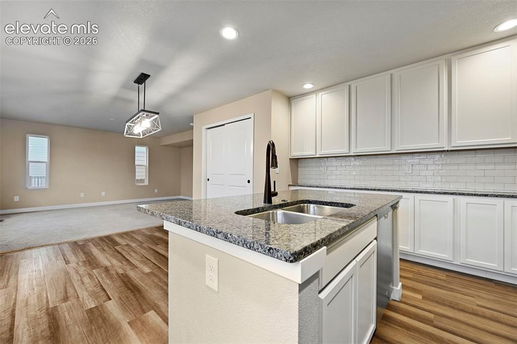 Image 3 of 28: Modern kitchen featuring an island with a double basin sink, granite counte