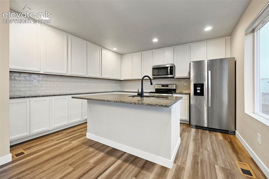 Image 4 of 28: Contemporary kitchen featuring white cabinetry, granite countertops, a subw