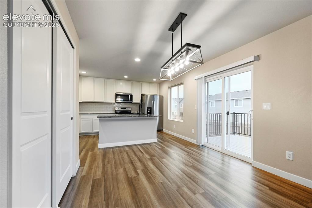 Image 5 of 28: Open-concept kitchen and dining area featuring wood-finish flooring, white