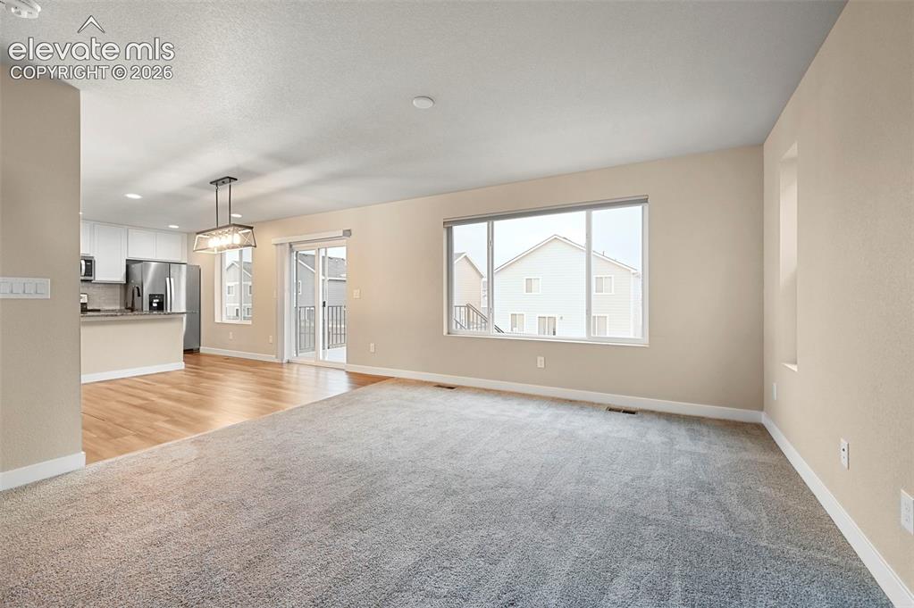 Image 8 of 28: Open-concept living space featuring light gray carpeting, wood-finish floor