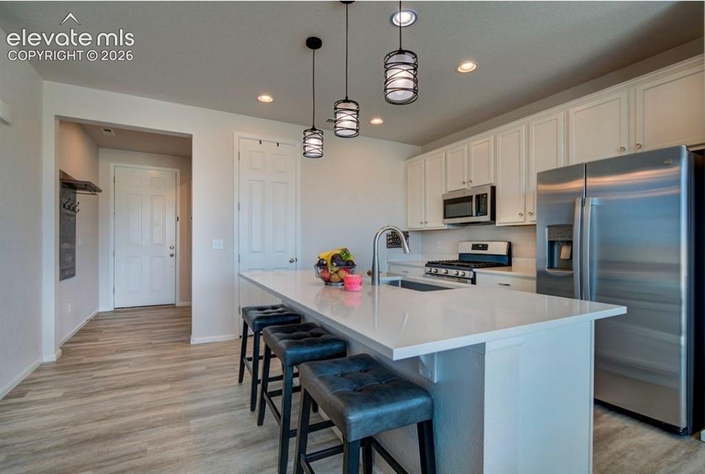Image 10 of 34: Kitchen featuring a large island with sink, stainless steel appliances, whi